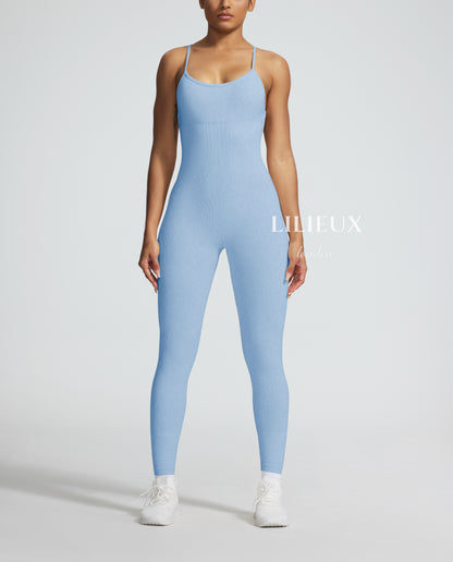 Model in a light blue graphic-patterned sports jumpsuit with thin straps, white sneakers, and socks, presenting a stylish and activewear-inspired fashion.