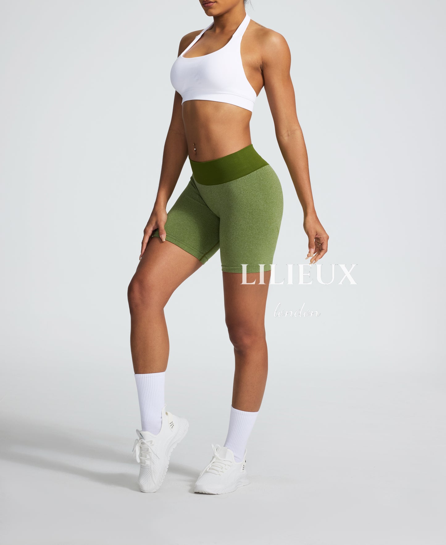 Side view of a woman wearing green compression biker shorts with a high-rise waistband, providing a sculpted fit and breathable fabric for fitness enthusiasts.
