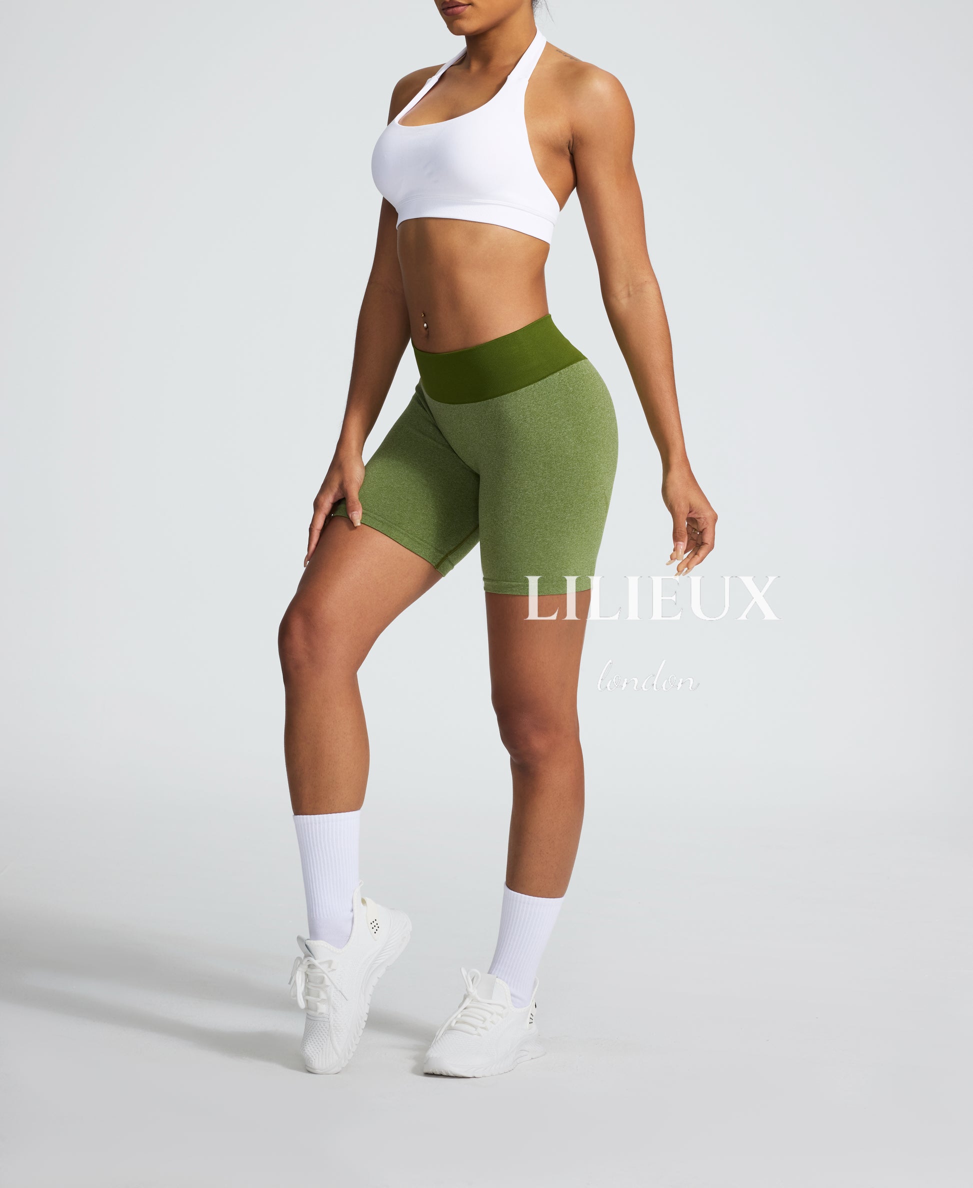 Side view of a woman wearing green compression biker shorts with a high-rise waistband, providing a sculpted fit and breathable fabric for fitness enthusiasts.