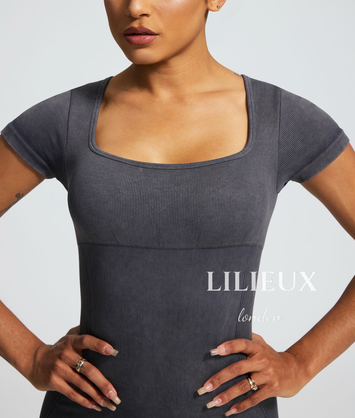 Close-up view of a grey sports romper with a square neckline, featuring a textured graphic pattern and highlighting the athletic fit.