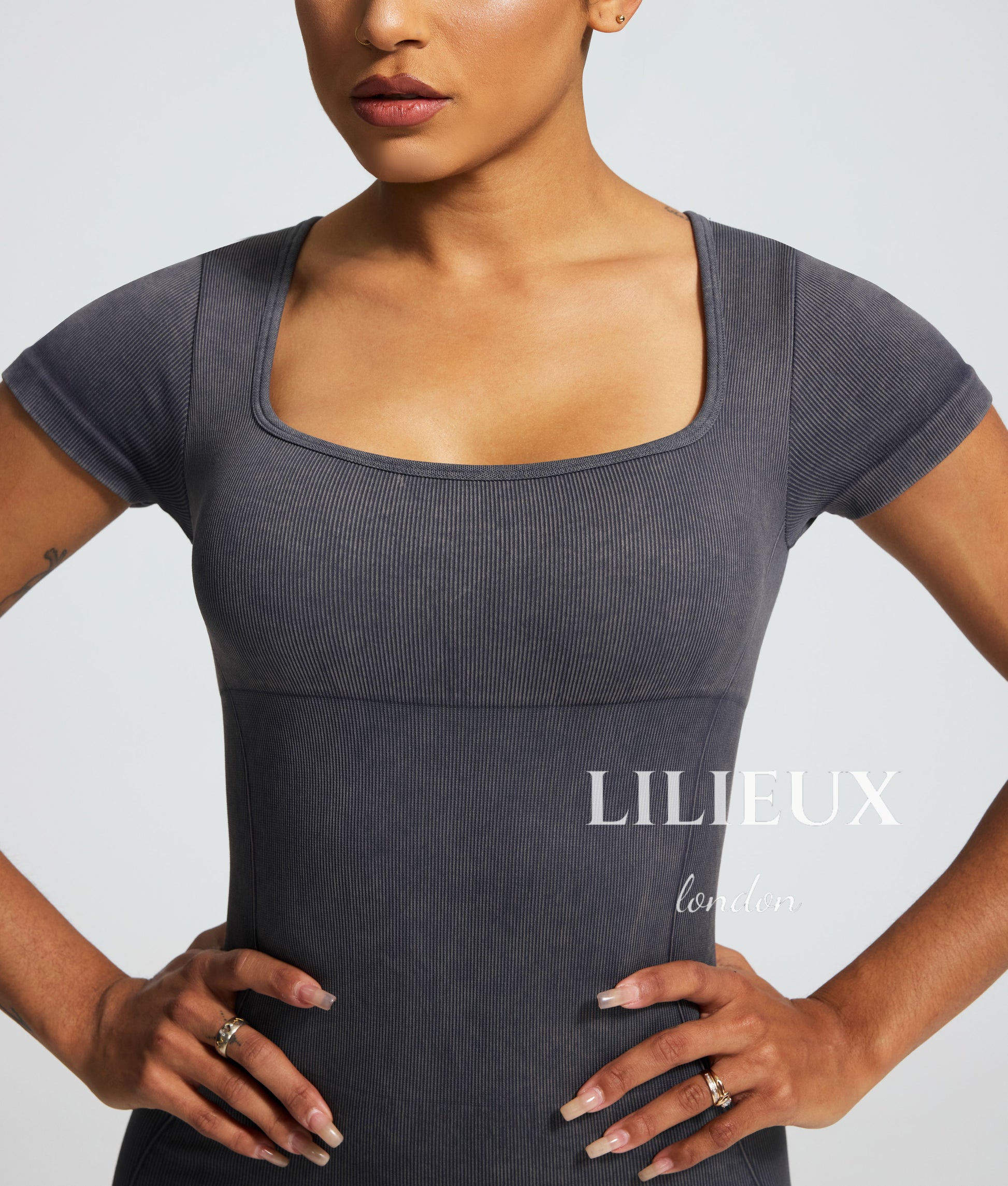 Close-up view of a grey sports romper with a square neckline, featuring a textured graphic pattern and highlighting the athletic fit.
