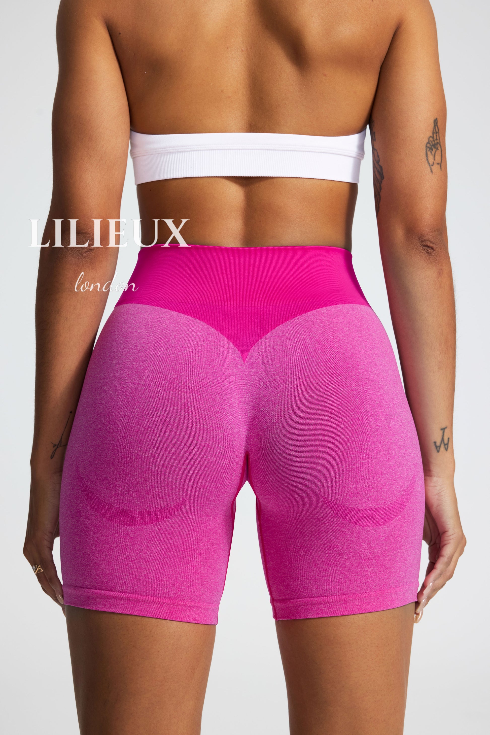 Back view of high-waisted scrunch-butt biker shorts in pink, featuring a ribbed compression waistband and contouring fabric, designed for gym and fitness performance."
