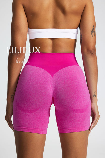 Back view of high-waisted scrunch-butt biker shorts in pink, featuring a ribbed compression waistband and contouring fabric, designed for gym and fitness performance."
